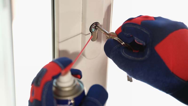 Worker in gloves checks lock in new plastic door or window. Repair and maintenance of locks in Ashford. Kent
