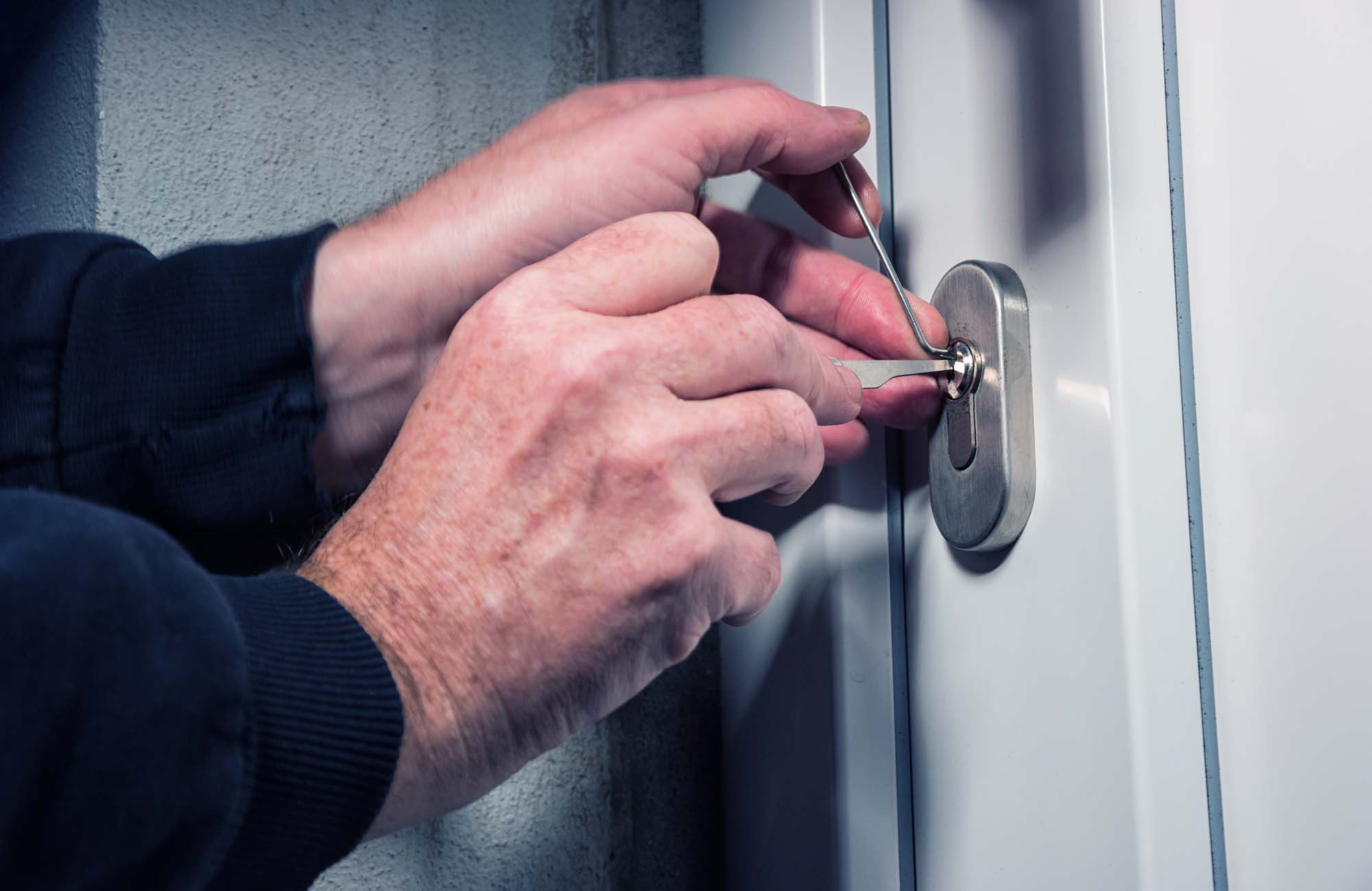 Intruder or burglar with lock picking tools. Intruder or Burglar with lockpick tool opens the front door to enter the house. could also be used for key service or locksmith concept in Ashford. Kent