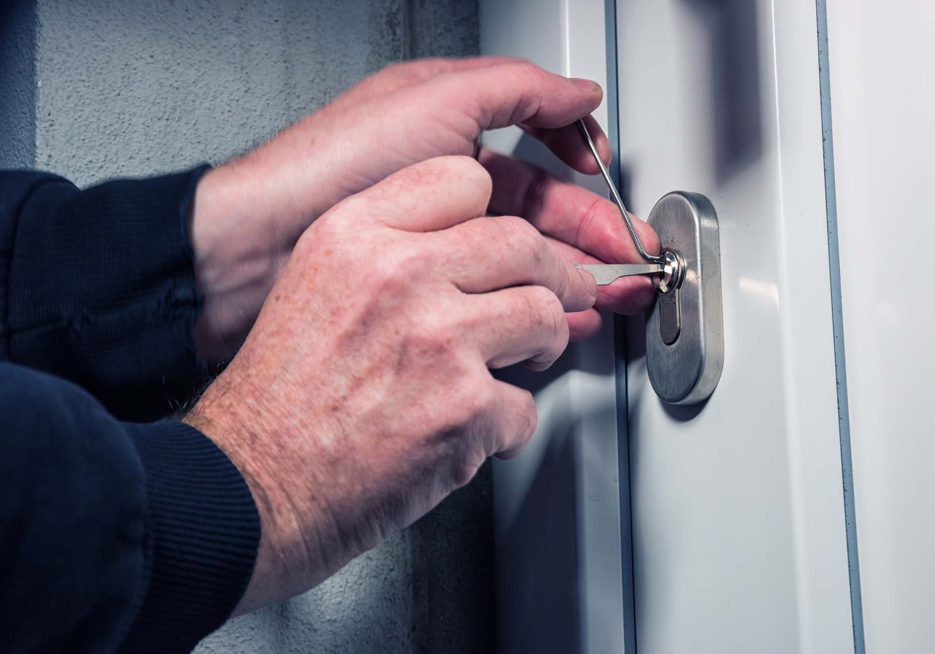 Intruder or burglar with lock picking tools. Intruder or Burglar with lockpick tool opens the front door to enter the house. could also be used for key service or locksmith concept in Ashford. Kent